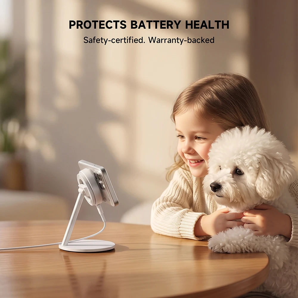 A child and a small white dog looking at a white smartphone on a white CoreDock charging stand on a wooden table, with top text reading “PROTECTS BATTERY HEALTH” and “Safety.” #color_white