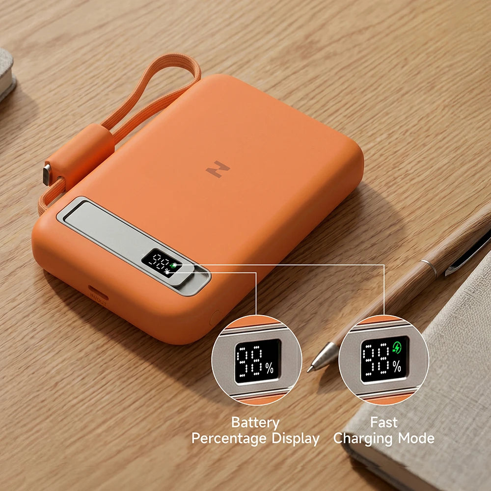 Orange MagAir magnetic wireless power bank with a digital battery display on a wooden surface.