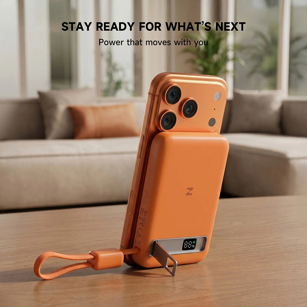 Orange MagAir semi-solid-state power bank magnetically attached to a phone on a table, with the text “Stay Ready for What's Next.” #color_orange
