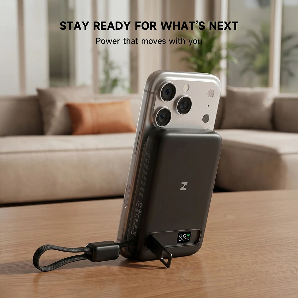 Smartphone with a MagAir magnetic power bank attached, placed on a table in a living room setting. #color_black