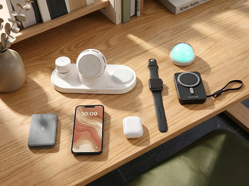 Various electronic devices on a wooden surface including a phone, smartwatch, and wireless chargers.