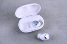 White wireless earbuds with charging case on gray background
