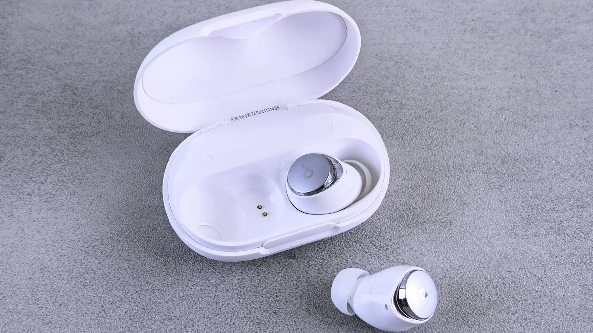 White wireless earbuds with charging case on gray background