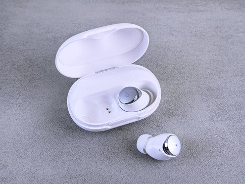 White wireless earbuds with charging case on gray background