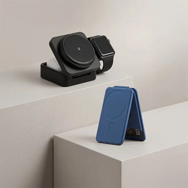 Black ZEEHOO FoldTrack 3-in-1 wireless charging station with a black smartwatch, and a separate blue magnetic card wallet on a light gray surface.