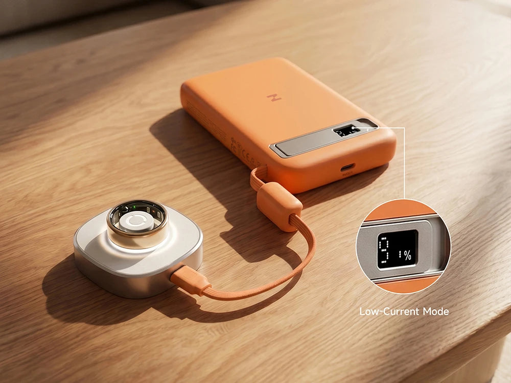Orange MagAir magnetic wireless power bank charging a smart ring on a wooden surface.