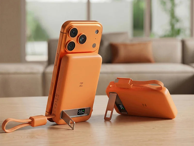 Orange smartphone attached to a ZEEHOO MagAir magnetic wireless power bank on a wooden tabletop with a softly blurred background.