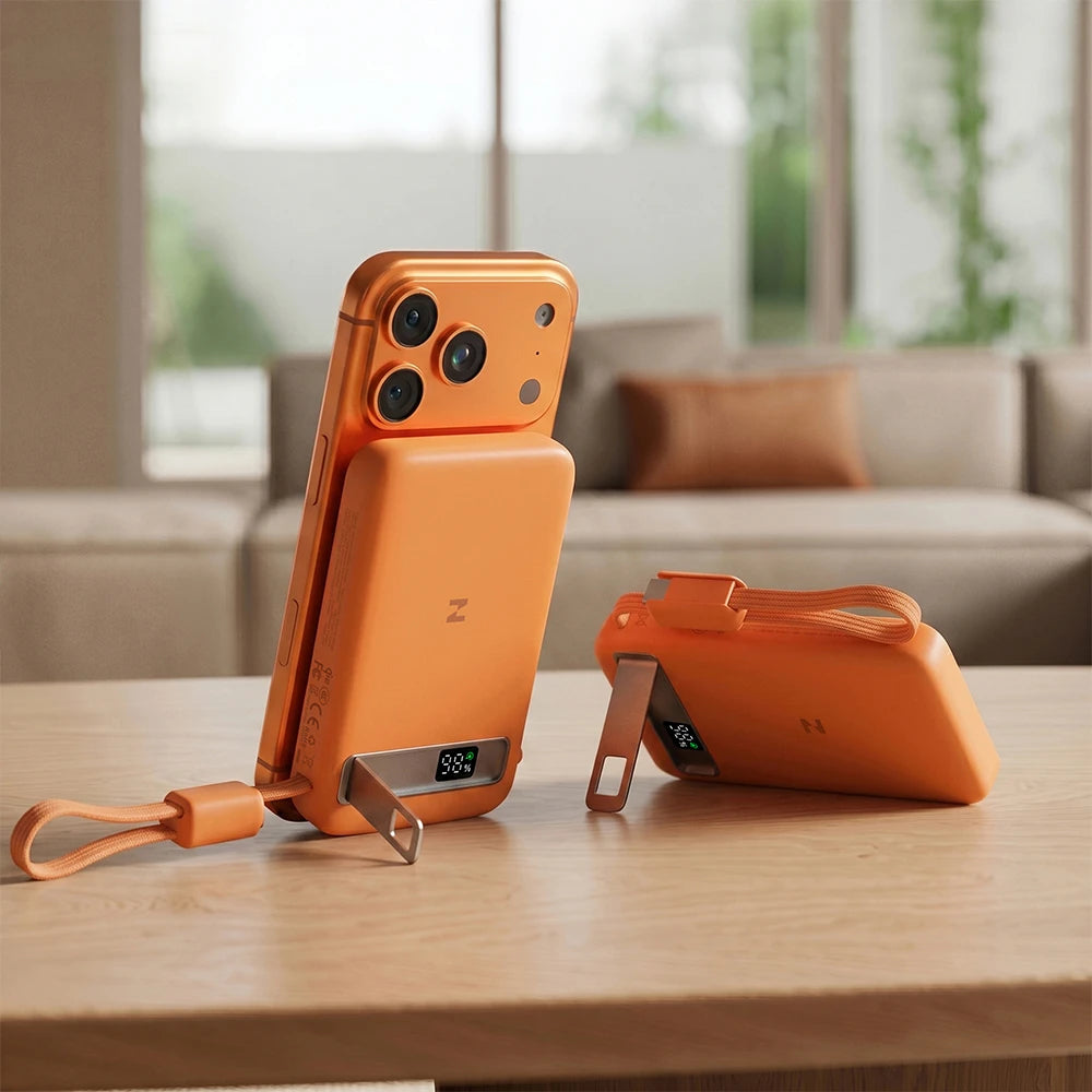 Orange smartphone with MagAir magnetic wireless power bank on a wooden table with a blurred background.
