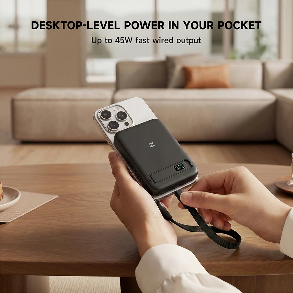 Person holding a smartphone with a MagAir magnetic power bank attached in a living room setting. #color_black