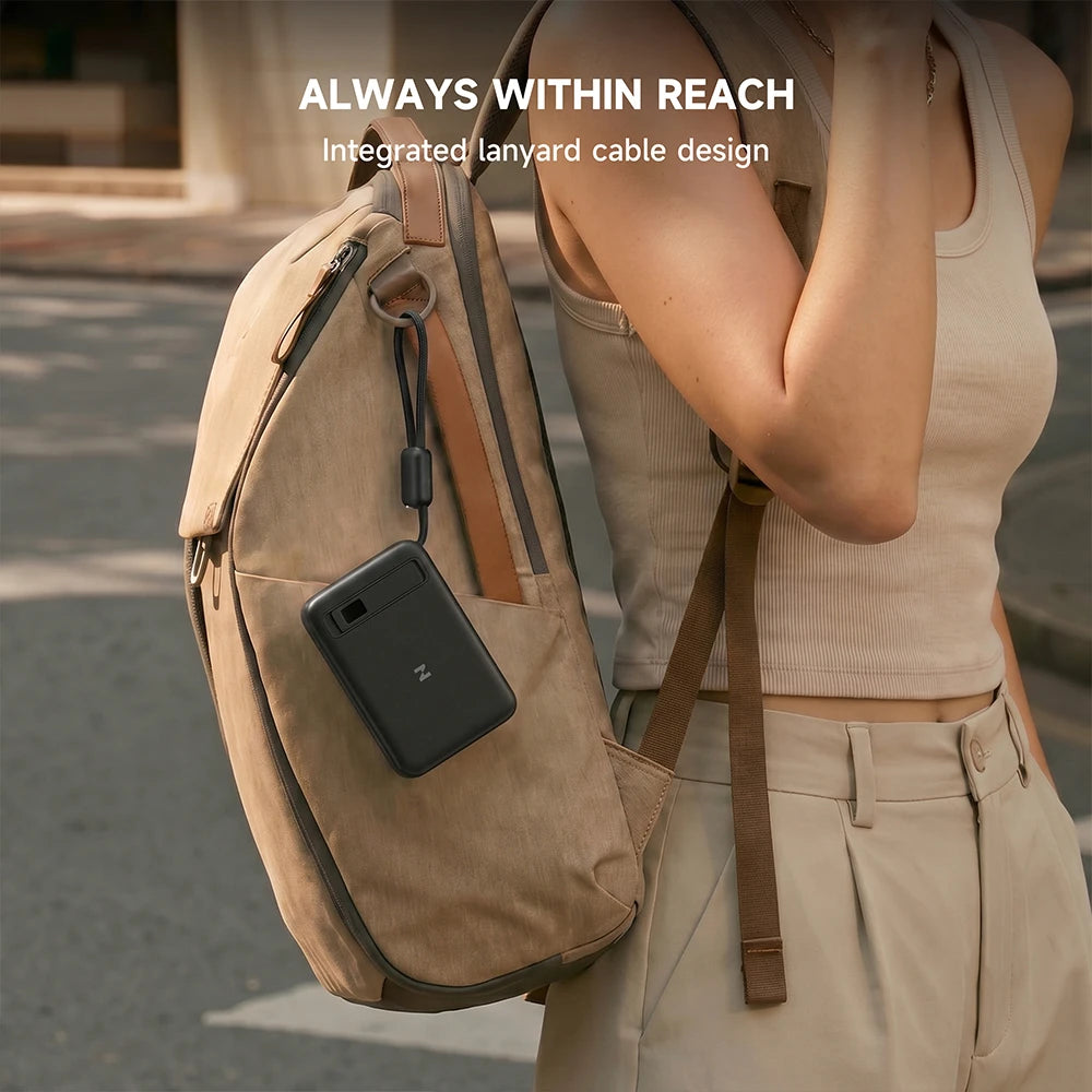 Person wearing a beige backpack with a black MagAir magnetic power bank attached, featuring an "Always Within Reach" message on a blurred street background. #color_black