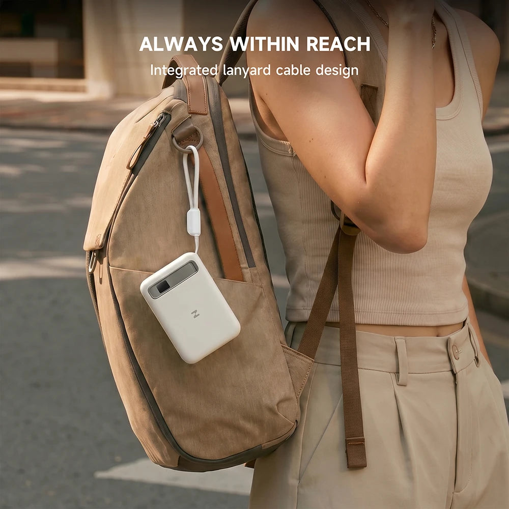 Person wearing a beige backpack with a white MagAir semi-solid-state power bank attached, featuring the text “Always Within Reach” on a blurred street background. #color_white
