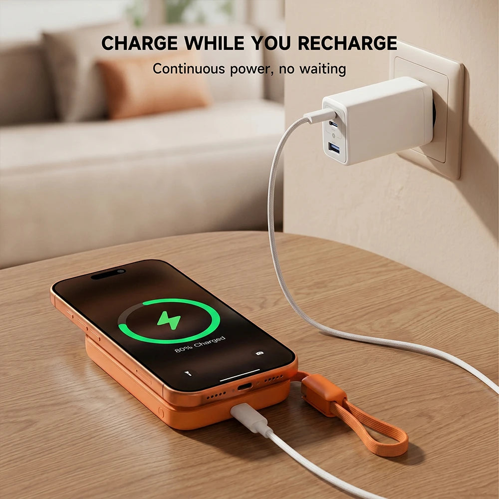 Phone connected to an orange MagAir semi-solid-state power bank on a table, with the power bank plugged into a wall outlet, featuring the text “Charge while you recharge.” #color_orange